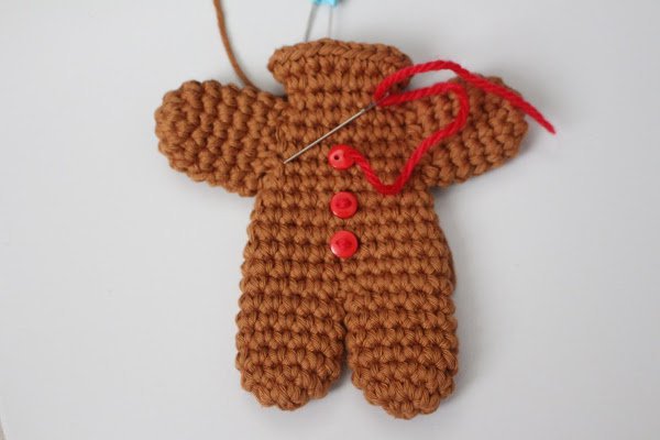 Crochet gingerbread man ornament assembly with 3 red buttons