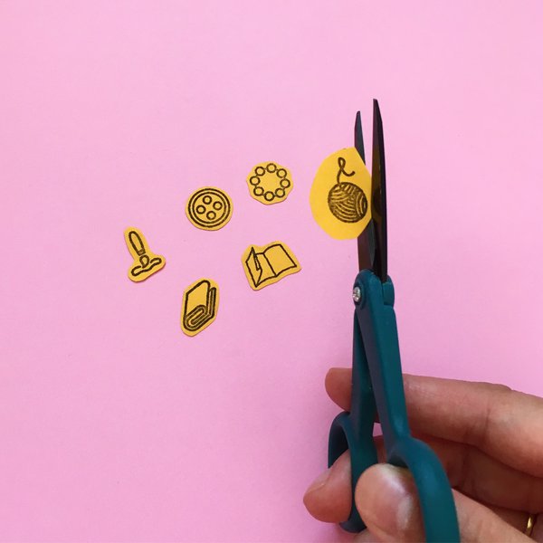 Closeup of hand fussy cutting icons on cardstock paper with scissors