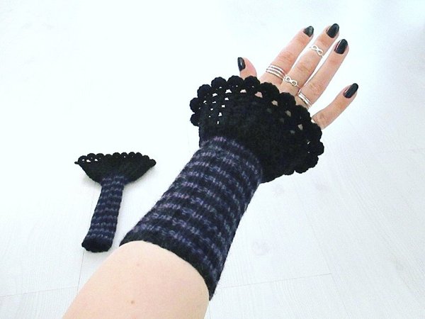 Ruffled and striped knit wristwarmers; one hand wearing wristwarmer, other wristwarmer on table