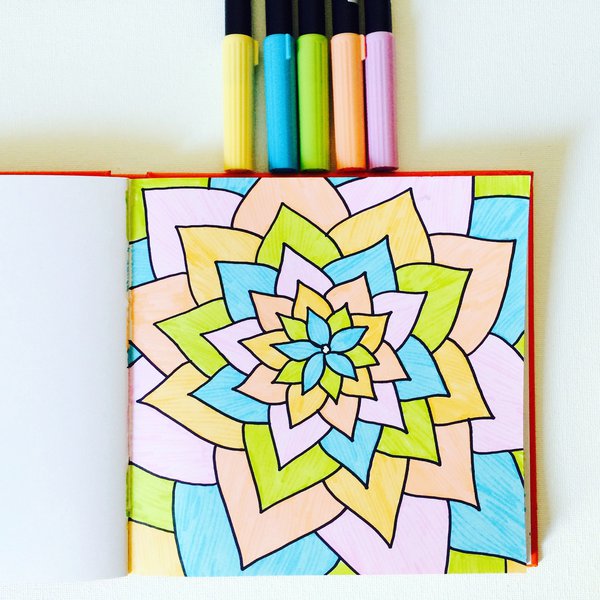 Mandala doodle drawing in sketchbook and set of markers