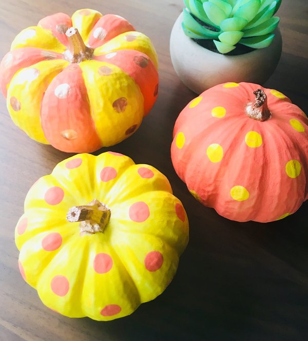 Three yellow and orange polka dot painted pumpkins and fake plant